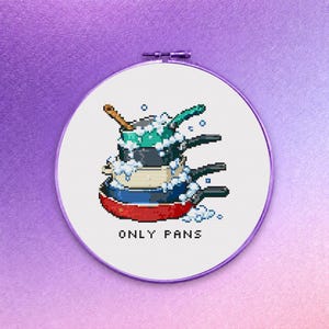 Könnte beinhalten: Kreuzstich-Stickerei in einem runden Rahmen, die einen Stapel pixeliger Töpfe und Pfannen mit Seifenblasen zeigt. Der Text "ONLY PANS" steht unter den Pfannen. Die Farbpalette umfasst Rot, Blau, Grün und Grau.