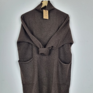 Könnte beinhalten: Ein braunes Rollkragenpulloverkleid mit zwei großen Taschen auf der Vorderseite. Das Kleid ist aus einem weichen, gestrickten Stoff.
