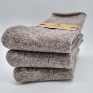 May include: Three pairs of brown wool socks stacked on top of each other. The socks are made of a soft, fuzzy material.