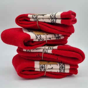 May include: A stack of four pairs of red and white patterned socks. The socks are folded and tied together with twine.