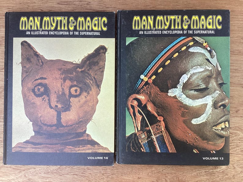 Puede incluir: Dos libros antiguos titulados "Man, Myth & Magic: An Illustrated Encyclopedia of the Supernatural". El volumen 14 presenta una m&aacute;scara de gato, mientras que el volumen 13 muestra a una persona con marcas tribales. Ambos libros tienen cubiertas negras.