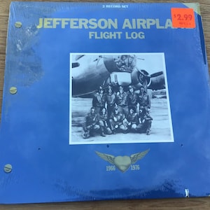 May include: A blue vinyl record album titled "Jefferson Airplane Flight Log." The album cover features a black and white photo of a group of people in front of an airplane. The album is a 2-record set.