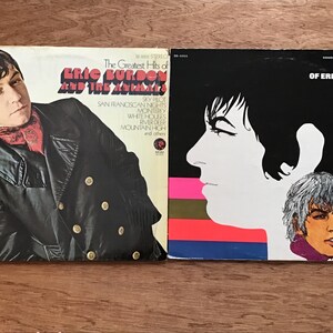 May include: Two vintage vinyl record albums. One album cover features a man in a black coat with the text "The Greatest Hits of Eric Burdon and The Animals." The other album cover has a profile of a woman with the text "The Best of Eric Burdon and The Animals Vol. II."