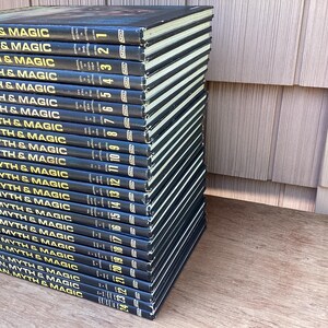 Puede incluir: Una pila de veintitr&eacute;s libros de tapa dura titulados "Man, Myth & Magic". Los libros tienen cubiertas azul oscuro con letras y n&uacute;meros dorados. Los lomos son visibles, mostrando el t&iacute;tulo de la serie y los n&uacute;meros de volumen.