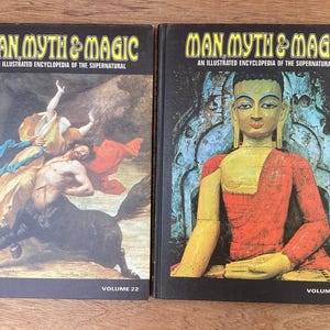 Puede incluir: Dos libros de tapa dura titulados "Man Myth & Magic: An Illustrated Encyclopedia of the Supernatural". El volumen 22 presenta una pintura de un centauro y figuras. El volumen 21 muestra una estatua de Buda sentado. Ambos libros tienen cubiertas negras.