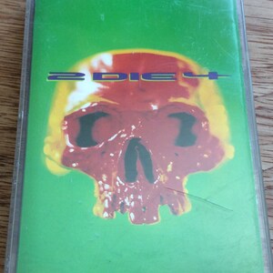 May include: A cassette tape with a green background and a red skull with yellow highlights. The text "2 DIE 4" is printed in purple on the front of the cassette.
