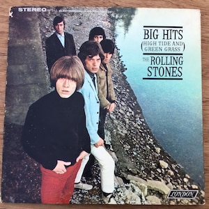 May include: Album cover for "Big Hits (High Tide and Green Grass)" by The Rolling Stones. The cover features a group photo of the band members in various outfits. The album title and band name are printed in white and black.