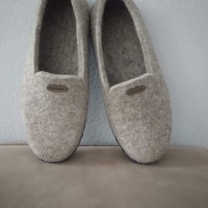 May include: A pair of gray felt slippers with a brown leather label that says "Handmade".