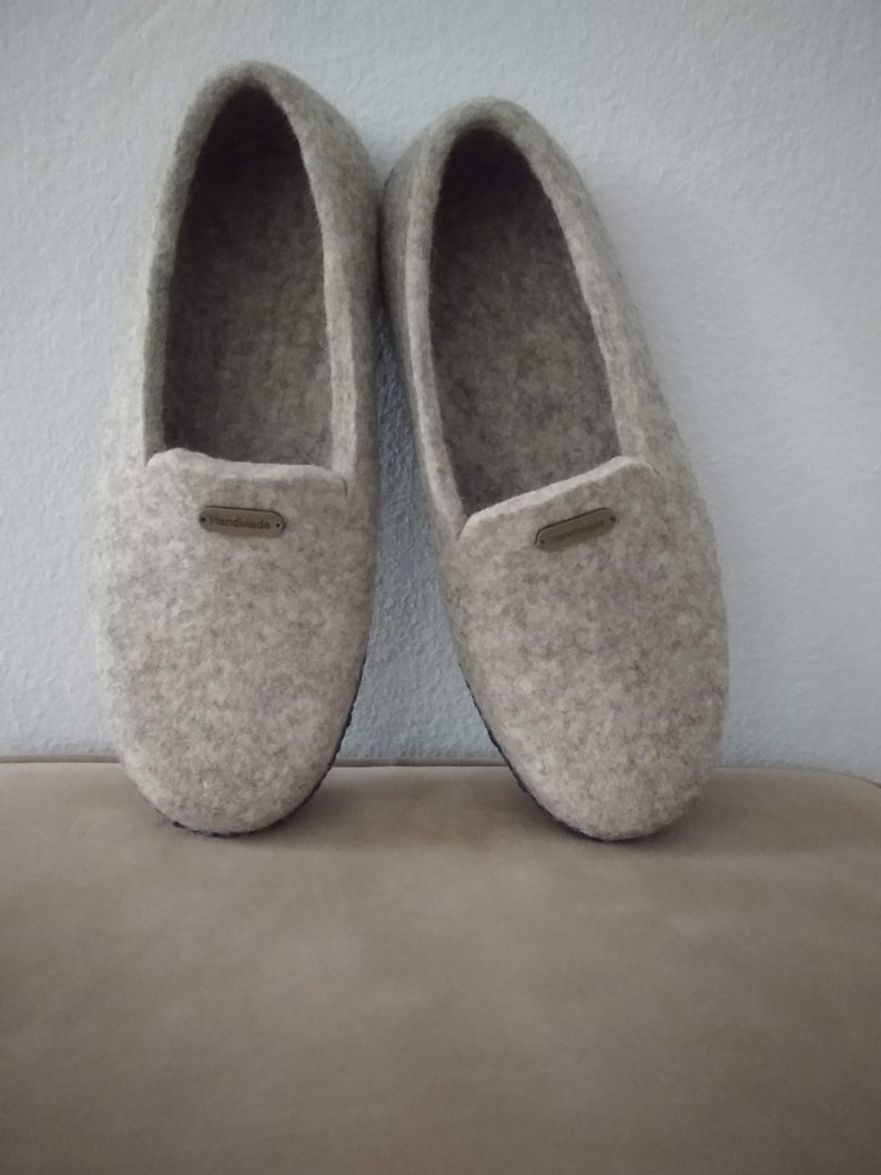 May include: A pair of gray felt slippers with a brown leather label that says "Handmade".
