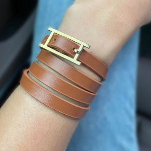 May include: A brown leather wrap bracelet with a gold-toned H-shaped buckle.