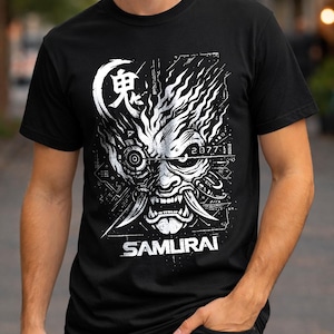 May include: A black short-sleeved t-shirt featuring a white graphic print of a stylized robotic samurai mask. The design includes the Japanese kanji for demon, the text 2077, and the word SAMURAI printed in a bold, sans-serif font at the bottom.