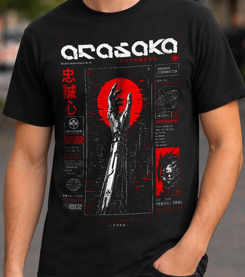May include: A black t-shirt featuring a graphic print of a robotic arm reaching toward a red circle. The design includes the text ARASAKA, Japanese characters, and technical diagrams in white and red ink, creating a detailed, industrial-style aesthetic.