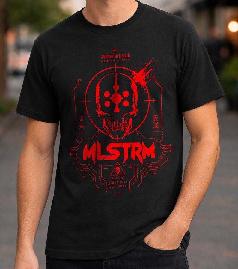 May include: A black short-sleeve t-shirt featuring a red graphic print of a skull centered within a circular target design. The text MLSTRM is printed below the skull, accompanied by circuit board patterns and additional text in English and Japanese.