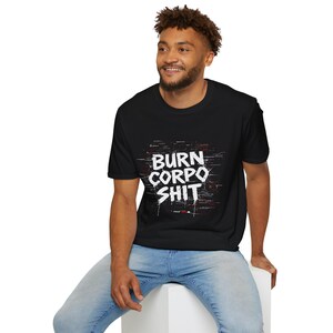 K&ouml;nnte beinhalten: Schwarzes T-Shirt mit dem wei&szlig;en Schriftzug "BURN CORPO SHIT" mit roten und wei&szlig;en Akzenten. Das T-Shirt besteht aus einem weichen Material und eignet sich f&uuml;r Freizeitkleidung.