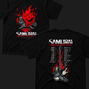Pu&ograve; includere: Una t-shirt nera con una grafica rossa e bianca di una maschera da samurai robotica sul davanti con il testo SAMURAI REUNION TOUR 2020. Il retro mostra un elenco di citt&agrave;, una chitarra elettrica nera e una mano robotica tra fiamme rosse.