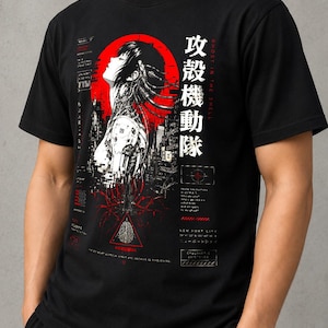 May include: A black short-sleeve t-shirt featuring a graphic print of a cyborg character with cables, a red circular background, and Japanese text reading 攻殻機動隊 alongside the English text Ghost in the Shell and New Port City.