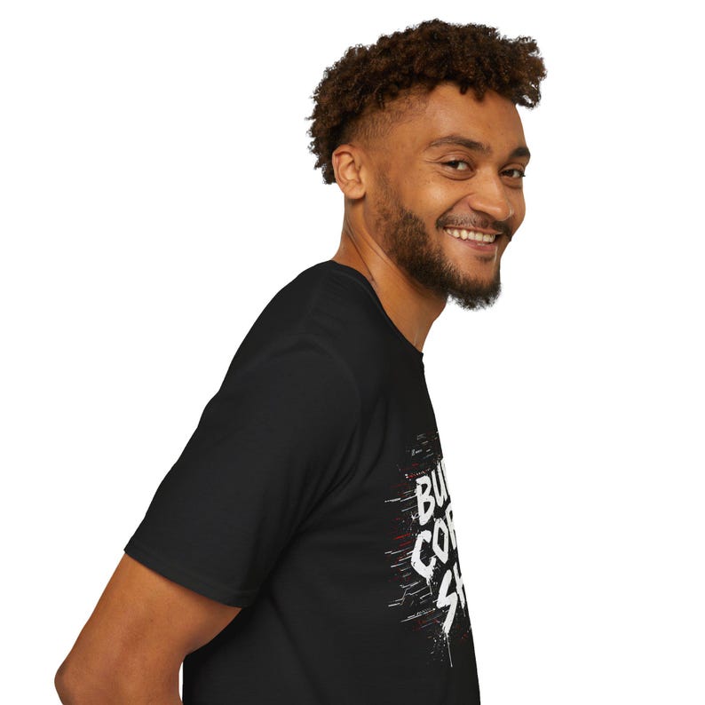 K&ouml;nnte beinhalten: Schwarzes T-Shirt mit wei&szlig;em und rotem Text "But First Coffee". Das Grafik-T-Shirt ist aus weichem Material und hat einen Rundhalsausschnitt. Die Person auf dem Bild l&auml;chelt.