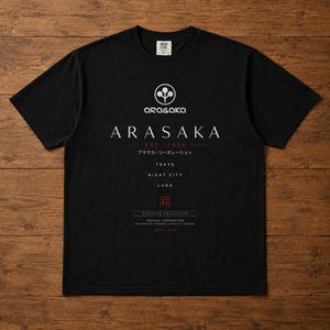 May include: A black short-sleeve t-shirt featuring a white Arasaka logo and text. The graphic includes the words ARASAKA, EST. 1919, TOKYO, NIGHT CITY, LUNA, and HERITAGE COLLECTION, along with Japanese characters and a small red square emblem.