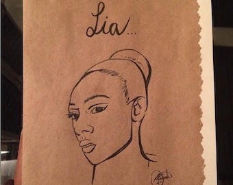 May include: A black and white line drawing of a woman's face on brown paper. The woman has her hair pulled back in a bun. The drawing is signed with the name "Lia..." in cursive.