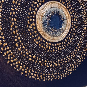 May include: A circular abstract painting with a gold and white center and a dark blue background. The center is surrounded by a ring of gold dots.