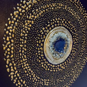 May include: A navy blue canvas painting with a gold and white circular design. The center of the circle features a blue and white agate stone.