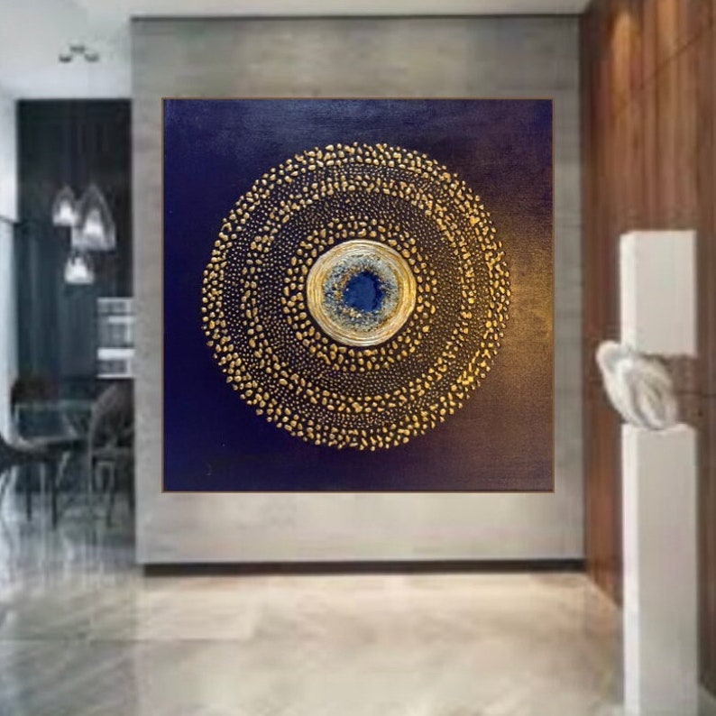 May include: A large abstract painting with a circular design in gold on a dark blue background. The center of the circle has a smaller circle with a blue and white design.