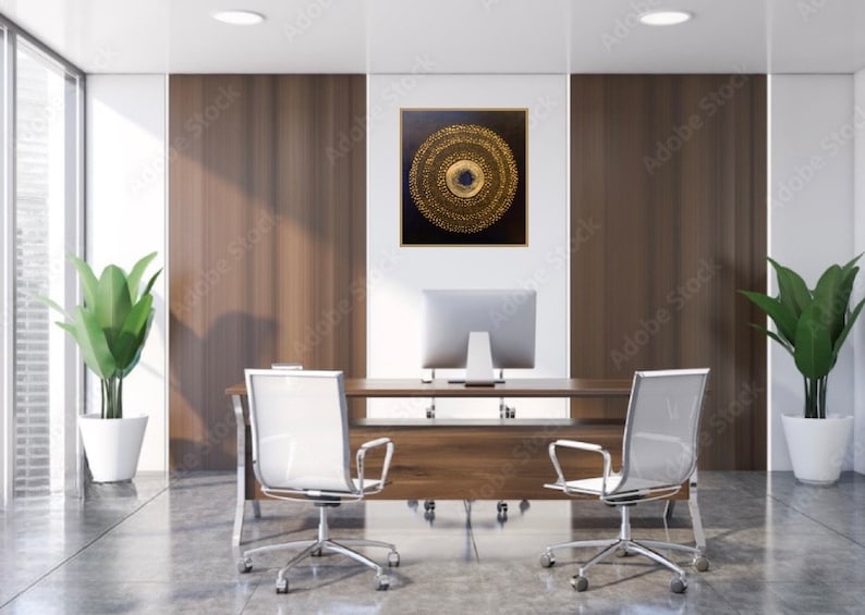 May include: A modern office interior with a wooden desk and two white mesh office chairs. A large framed abstract painting with gold and black concentric circles hangs on the wall behind the desk.