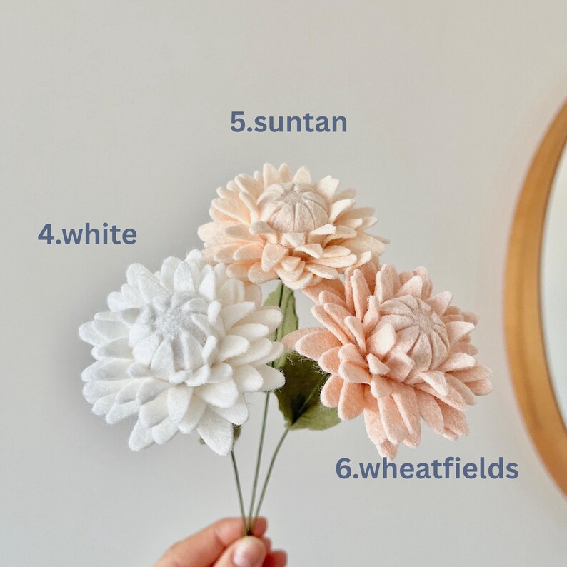 May include: Three felt flowers on thin green stems. The flower labeled 4.white is white, 5.suntan is a light peach, and 6.wheatfields is a soft tan. Each flower has multiple layers of rounded petals and a textured center, creating a full bloom.