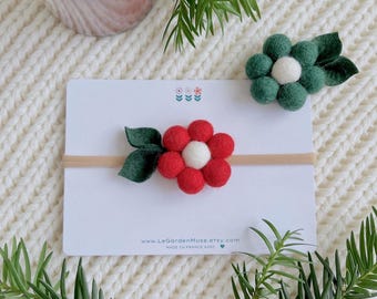 May include: A beige elastic headband featuring a felt flower made of red spheres with a white center and two dark green felt leaves. The headband is attached to a white display card with the text www.LeGardenMuse.etsy.com and MADE IN FRANCE.