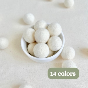 May include: A small white bowl filled with several round, textured white felt balls. Additional white felt balls are scattered around the bowl. A green rectangular graphic in the corner displays the white text 14 colors.