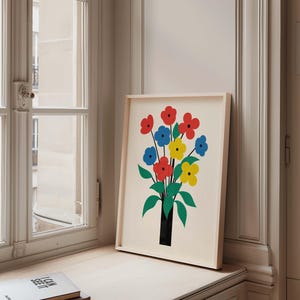 May include: A framed print of a colorful abstract floral bouquet in a black vase. The flowers are red, yellow, and blue. The background is white.