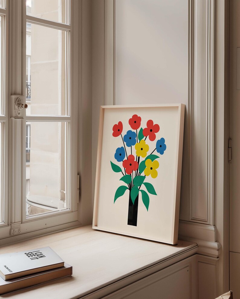 May include: A framed print of a colorful abstract floral bouquet in a black vase. The flowers are red, yellow, and blue. The background is white.