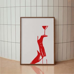 May include: A red illustration of a high heel shoe holding a martini glass. The illustration is framed in a brown wood frame.