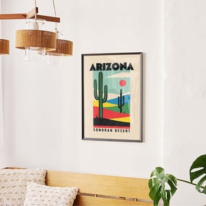 Może przedstawiać: Ramka z plakatem w retro stylu przedstawiającym zielony kaktus i tekst "Arizona Sonoran Desert". Plakat ma kolorystykę niebieską, zieloną, czerwoną, ż&oacute;łtą i czarną.