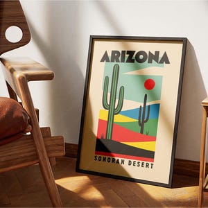 Może przedstawiać: Ramka z plakatem w retro stylu przedstawiającym duży zielony kaktus i mniejszy kaktus na pustyni Sonora. Plakat zawiera tekst "Arizona" i "Sonoran Desert" czarnymi literami.