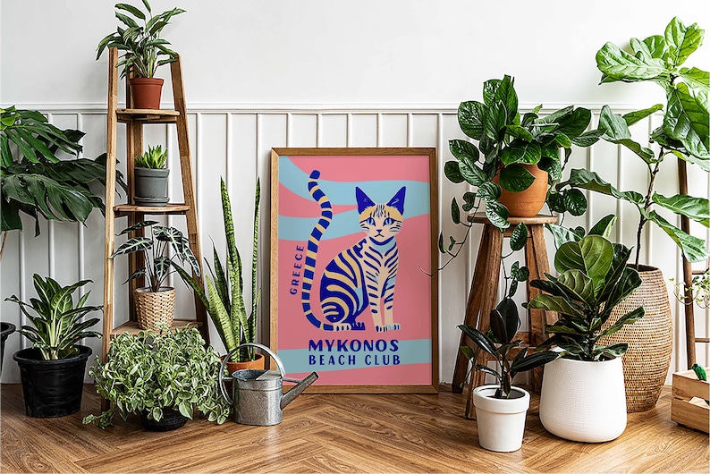 May include: A colorful poster with a blue and yellow striped cat sitting on a pink background. The poster says "Greece" and "Mykonos Beach Club".