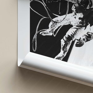 K&ouml;nnte beinhalten: Schwarzwei&szlig;foto eines Astronauten, der im Weltraum schwebt und an einem Raumschiff befestigt ist. Der Astronaut tr&auml;gt einen Raumanzug und h&auml;lt sich an einem Seil fest.