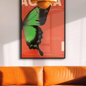 May include: A framed poster featuring a green and black butterfly design on a red backdrop. The poster has Portuguese text, including "Museu do Ar" and "Sintra, Portugal". An orange pendant light hangs above an orange leather sofa.
