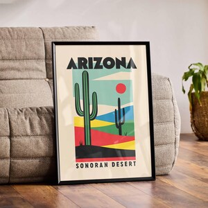 Może przedstawiać: Czarny plakat w ramie z kolorową ilustracją pustynnego krajobrazu. Plakat zawiera napis "Arizona Sonoran Desert" i przedstawia duży zielony kaktus oraz mniejszy kaktus w tle.