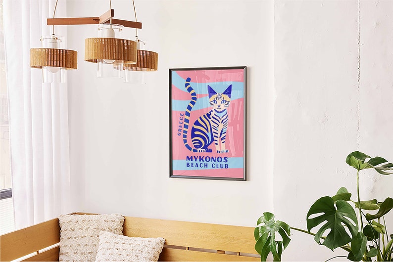 May include: A colorful poster with a blue and yellow striped cat sitting on a pink background. The poster says "Greece" and "Mykonos Beach Club".