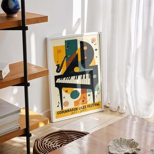 May include: A white framed poster with a colorful abstract design of a piano and a saxophone. The poster reads "Copenhagen Jazz Festival" with the dates "July 8 - July 16".