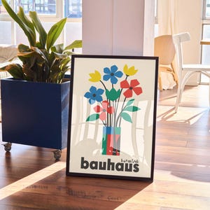 Pu&ograve; includere: Un poster incorniciato con un'illustrazione colorata di un mazzo di fiori in un vaso. Il vaso &egrave; composto da forme geometriche colorate. Il poster ha il testo "bauhaus" in basso.