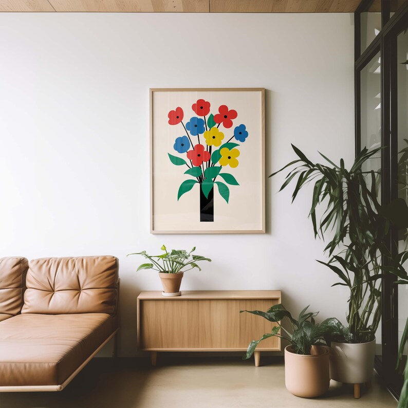 May include: A framed print of a colorful flower bouquet in a black vase. The flowers are red, yellow, and blue. The print is hanging on a white wall above a wooden cabinet.