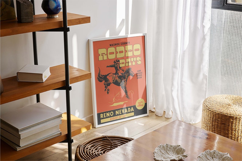 K&ouml;nnte beinhalten: Ein gerahmtes Poster mit einem Vintage-Design, das f&uuml;r die "Washoe County Rodeo Days" in Reno, Nevada wirbt. Das Poster zeigt einen Cowboy, der ein wildes Pferd reitet, mit dem Text "August 23-29" und "12th Annual" in der rechten unteren Ecke.