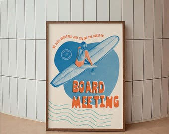 May include: A framed poster with a vintage surf theme. The artwork features a person in an orange swimsuit sitting on a surfboard, set against a blue heart shape. Text includes "NO SUITS REQUIRED. JUST YOU AND THE HORIZON" and "BOARD MEETING."