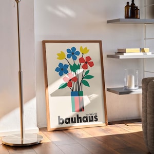 Pu&ograve; includere: Una stampa incorniciata di un arrangiamento floreale colorato in un vaso con la parola "bauhaus" stampata sotto. La stampa &egrave; su sfondo bianco e ha una cornice in legno.