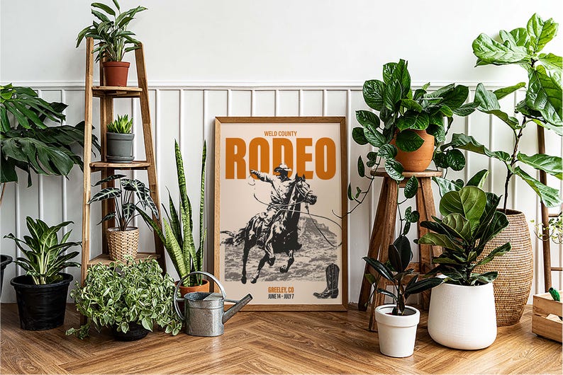 Pode incluir: Um p&ocirc;ster de estilo vintage com o texto "Weld County Rodeo" em letras laranja sobre um fundo creme. O p&ocirc;ster apresenta um caub&oacute;i montando um cavalo que se debate. O p&ocirc;ster est&aacute; emoldurado e pendurado em uma parede branca.
