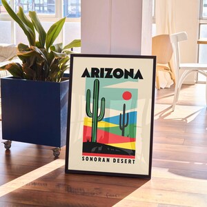 Może przedstawiać: Czarny plakat w ramie z kolorową ilustracją pustynnego krajobrazu z dwoma kaktusami i tekstem "Arizona Sonoran Desert".