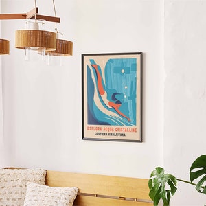 May include: A framed vintage travel poster with a blue and green illustration of a woman diving into the water. The text on the poster reads "Esplora Acque Cristalline Costiera Amalfitana".