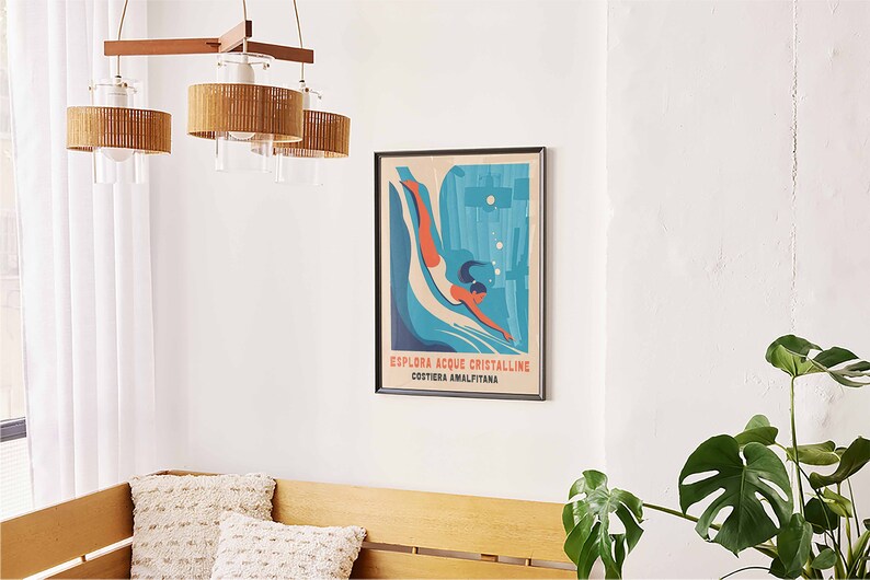 May include: A framed vintage travel poster with a blue and green illustration of a woman diving into the water. The text on the poster reads "Esplora Acque Cristalline Costiera Amalfitana".